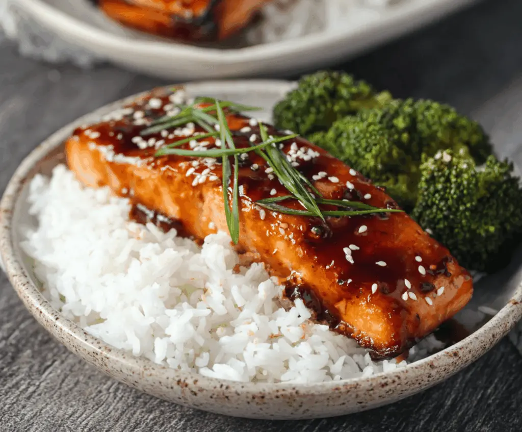 Delicious savory teriyaki salmon glazed with shiny sauce, served with fresh vegetables on a plate