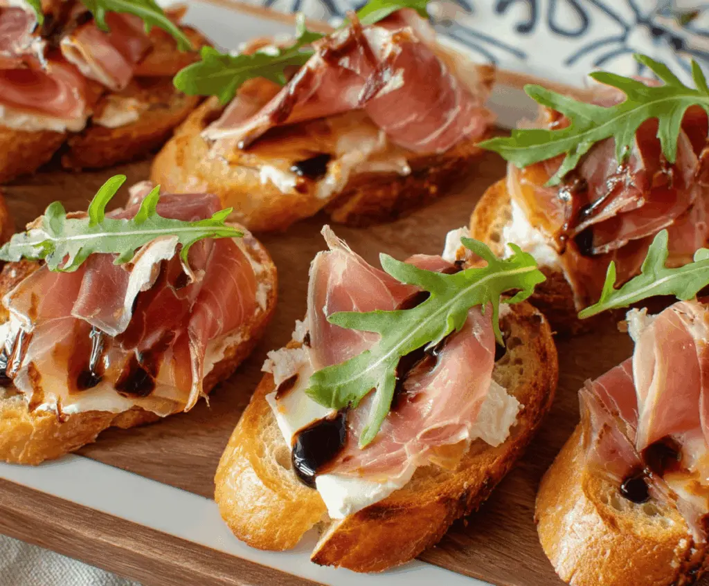 Delicious Brie and Prosciutto Crostini on a wooden platter with fresh herbs.
