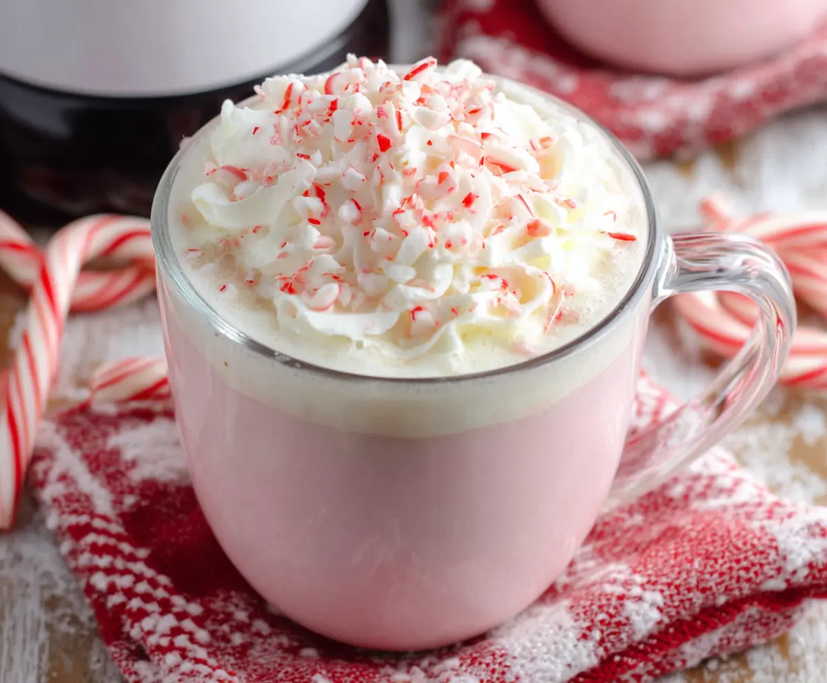 Creamy Crockpot Candy Cane White Hot Chocolate in a mug with whipped cream and peppermint garnish.