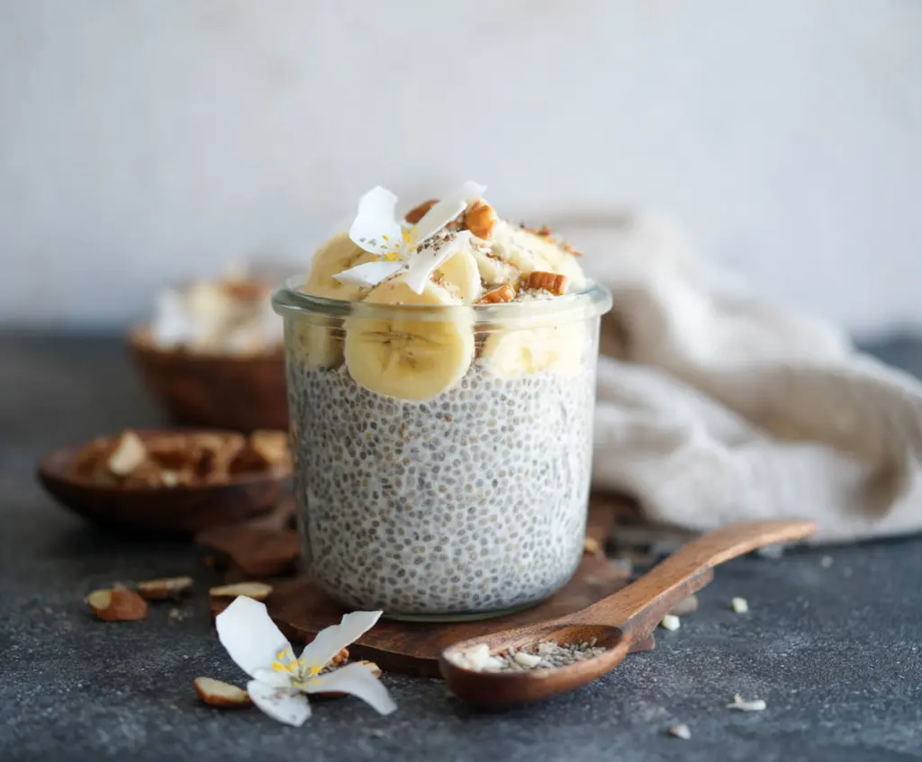 Creamy banana coconut milk chia seed pudding served in a glass bowl, garnished with fresh banana slices and coconut shavings.