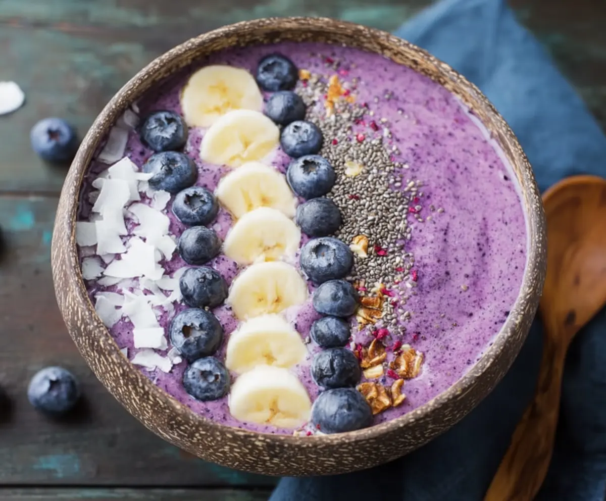 Fresh blueberry smoothie bowl topped with sliced fruits, granola, and chia seeds for a healthy breakfast