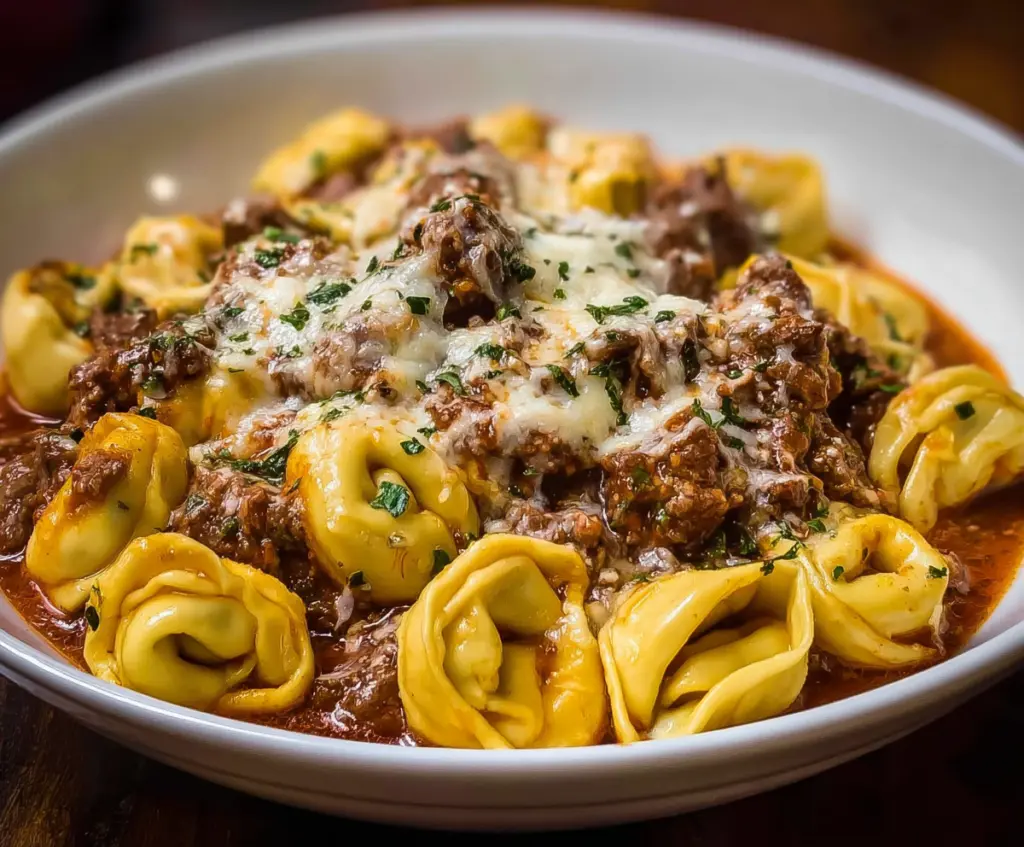 Delicious cheesesteak tortellini dish with melted cheese and savory beef filling served on a white plate