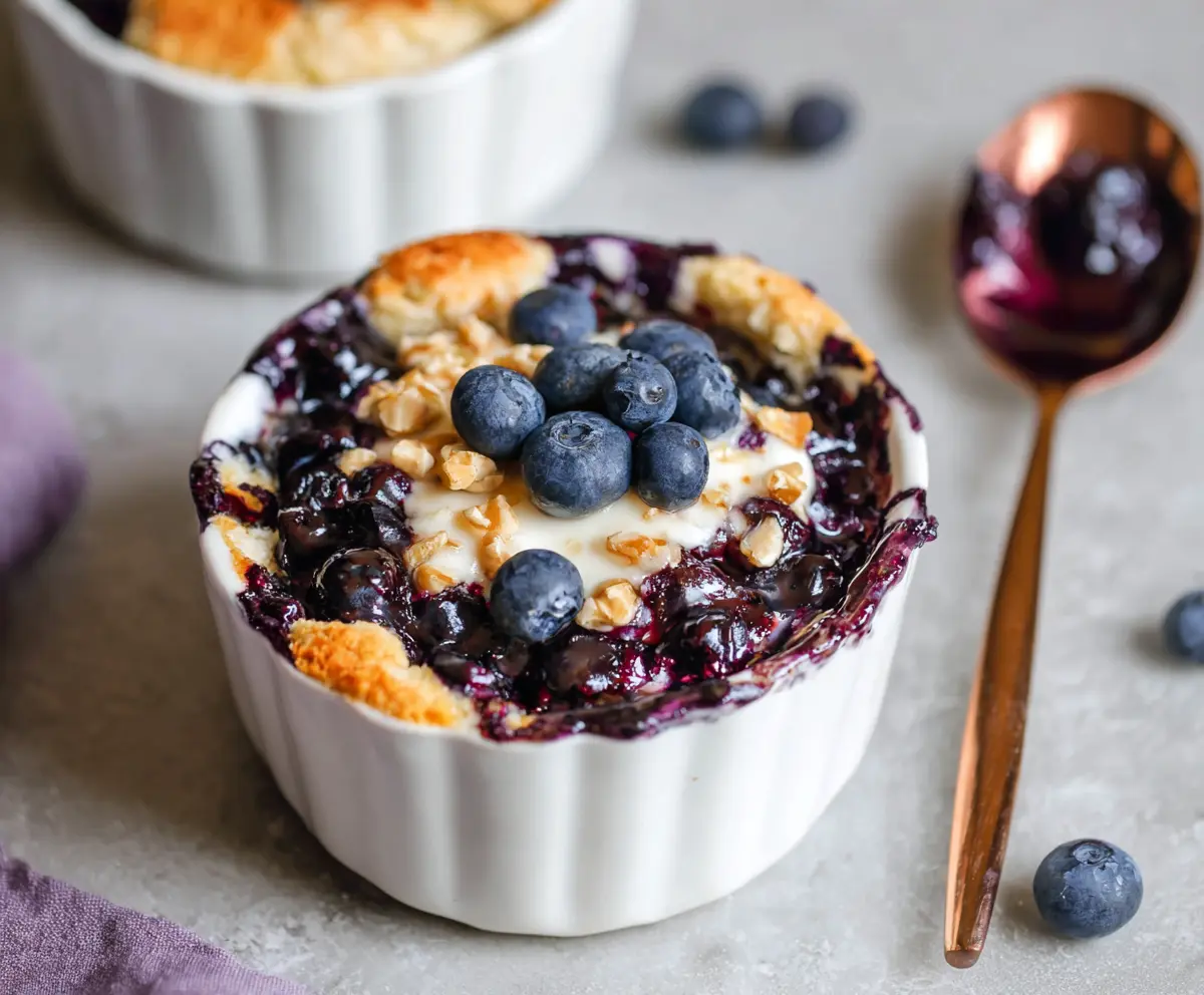 Baked blueberry cottage cheese breakfast bowls served in a bowl with fresh blueberries and a sprinkle of honey.