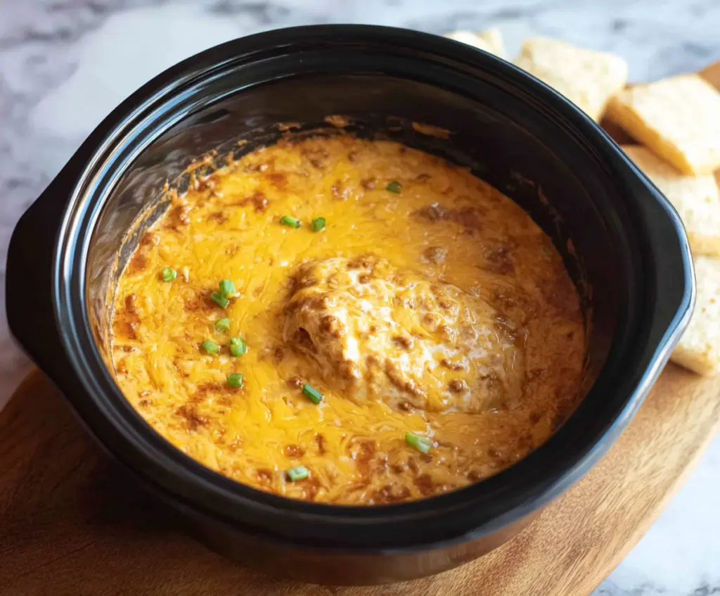 Delicious Crockpot Chili Cheese Dip served in a bowl with tortilla chips on a rustic table.