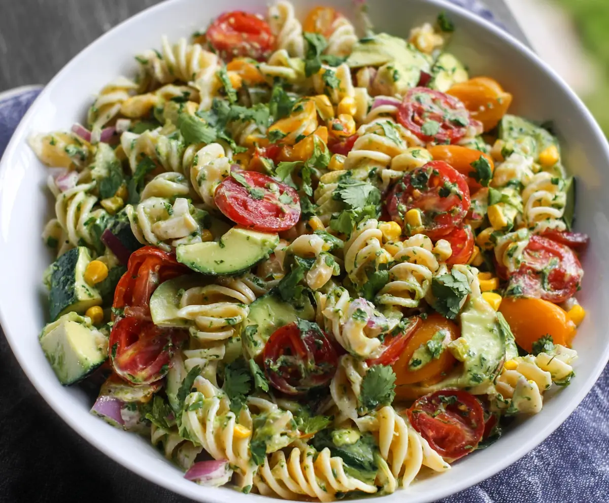 Fresh cilantro and lime pasta salad served in a white bowl, vibrant and colorful for a refreshing summer dish.
