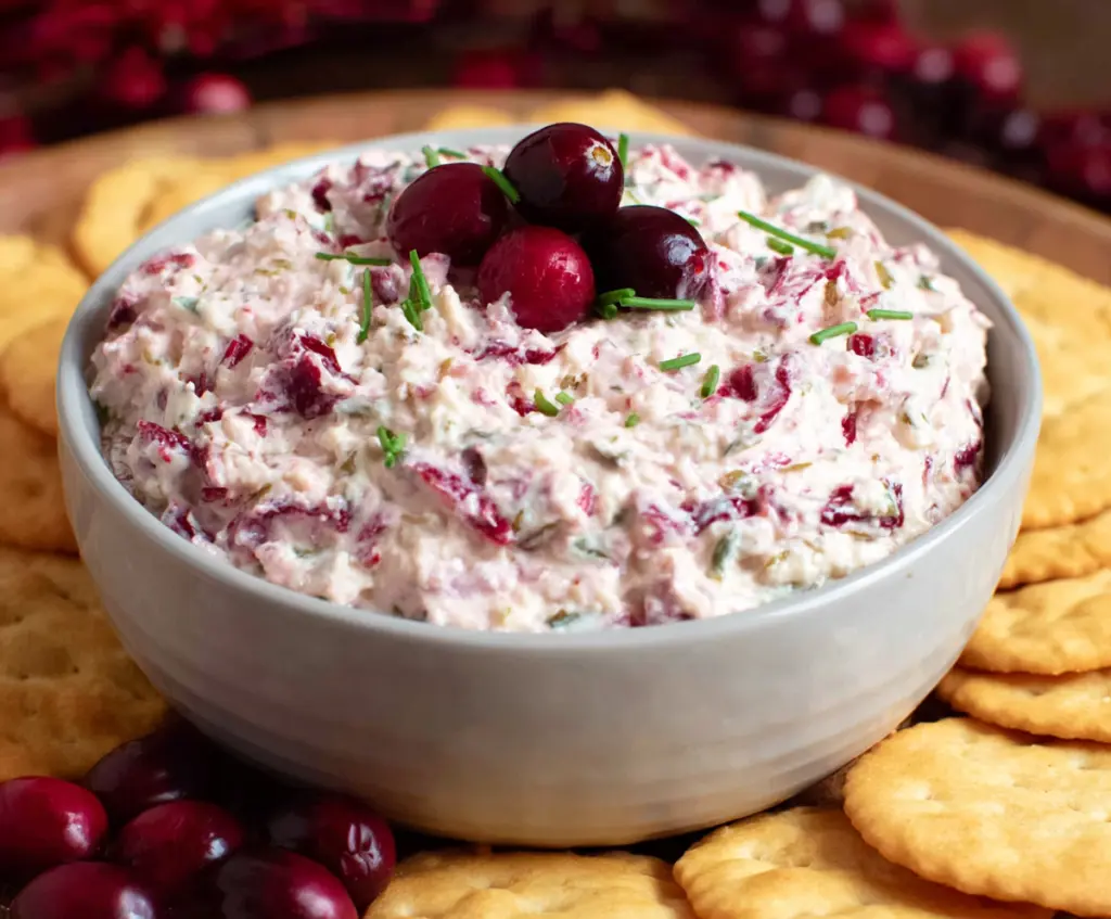 Creamy cranberry jalapeno dip with fresh herbs in a bowl, perfect for appetizers and parties.