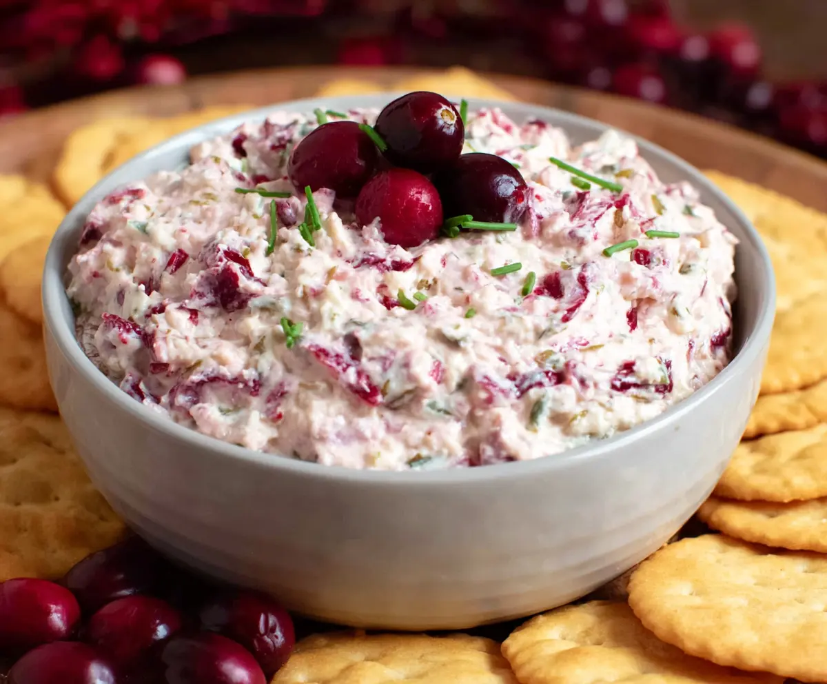 Creamy cranberry jalapeno dip with fresh herbs in a bowl, perfect for appetizers and parties.