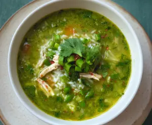 Delicious Green Garlic and Ginger Chicken and Rice Soup served in a bowl with fresh herbs