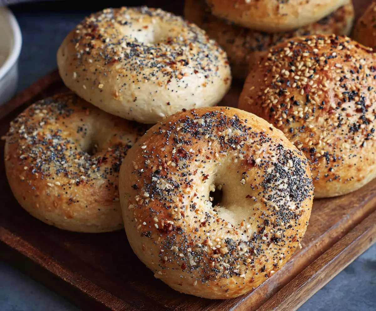 Homemade no yeast sourdough discard bagels on a wooden surface, showcasing their golden-brown crust.