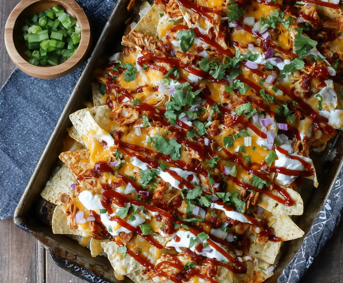 Delicious sheet pan BBQ chicken nachos topped with melted cheese and fresh toppings.
