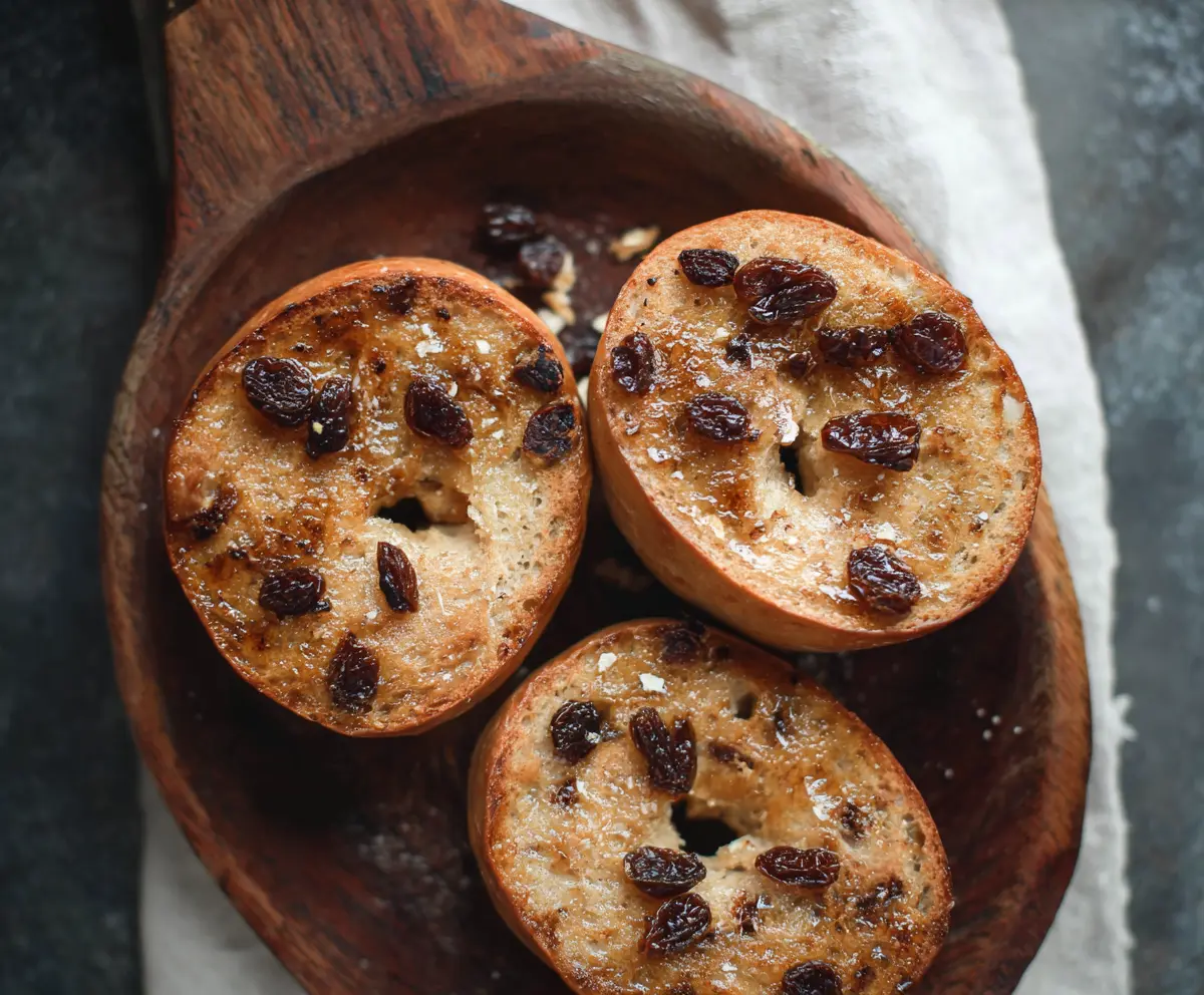 Delicious homemade cinnamon raisin Greek yogurt bagels on a plate, showcasing a warm, fresh-baked appearance.
