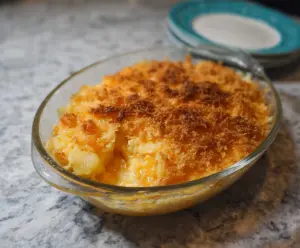 Delicious pineapple cheese casserole served in a baking dish, topped with melted cheese and fresh pineapple slices.